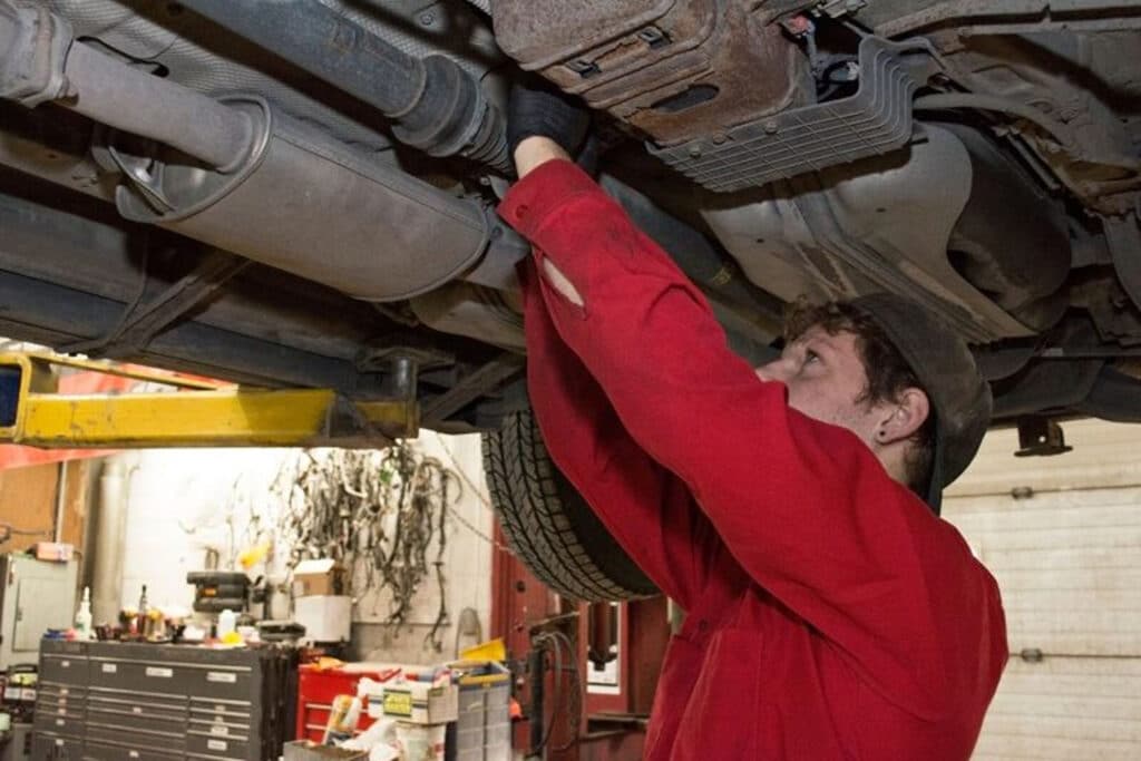 Karl (co-owner of Bear's Repair) working on the underside of a car in a red shirt.