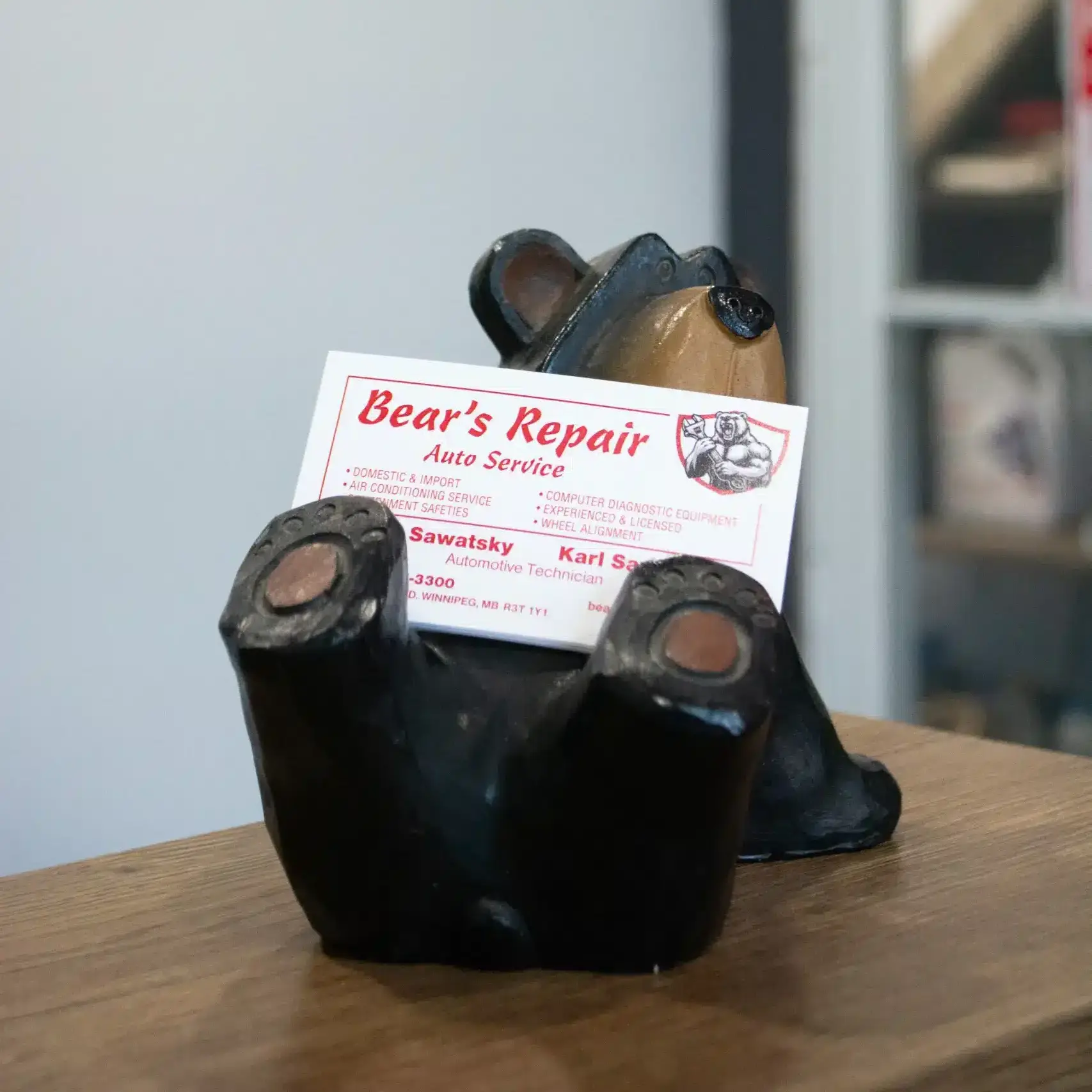 A "Bear's Repair Auto Service" business card on a bear-shaped business card holder on a desk